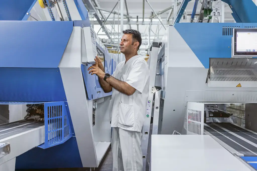 Ein Mitarbeiter bedient ein digitales Kontrollpanel in einem technischen Unternehmensraum in Ulm.