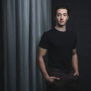 Ausdrucksstarkes Porträt eines jungen Unternehmers vor einem dunklen Hintergrund in Ulm.