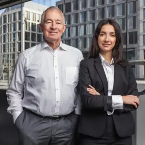 Ein professionelles Business-Porträt eines Mannes und einer Frau in geschäftlicher Kleidung vor einer modernen Bürogebäude-Fassade in Ulm.