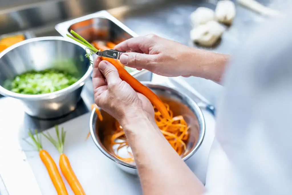 Hände eines Mitarbeiters beim Schneiden von Lauchzwiebeln in einer Ulmer Profiküche.