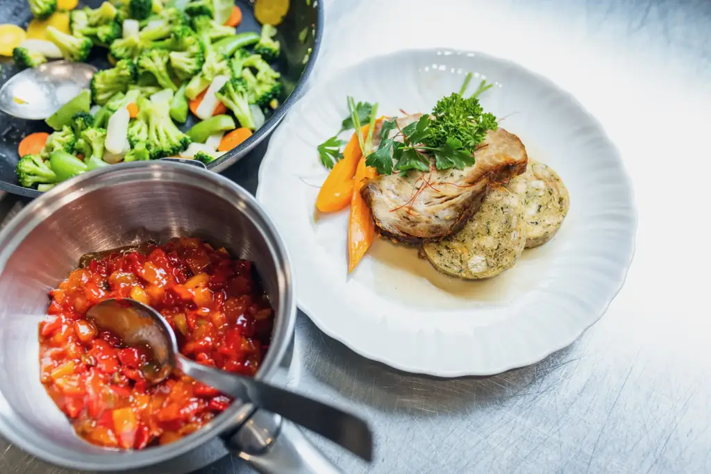 Ein lächelndes Team aus zwei Mitarbeitern in Berufsbekleidung in einer modernen Gastronomie-Küche in Ulm.