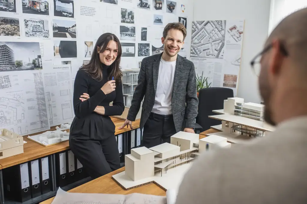 Zwei Architekten besprechen Details an einem physischen Architekturmodell in einem Ulmer Büro.