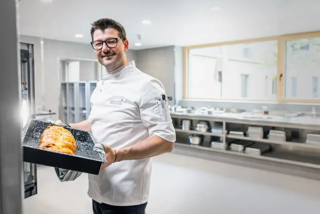 Mitarbeiter beim Entnehmen eines Backblechs im betrieblichen Alltag eines Ulmer Unternehmens.