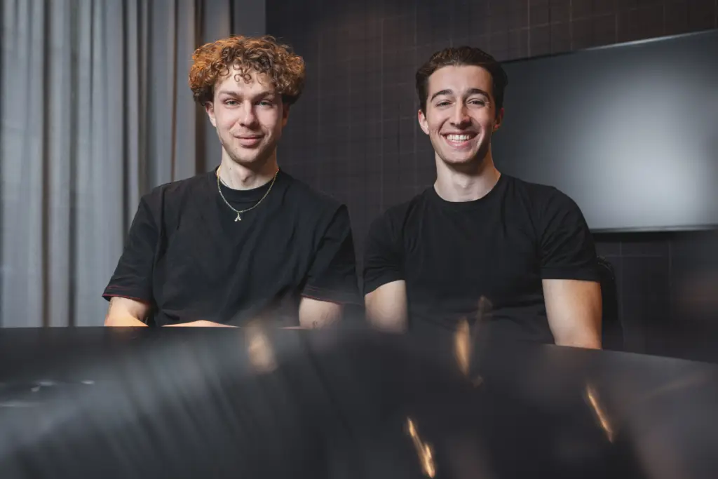 Sympathisches Porträt von zwei jungen Gründern in schwarzer Kleidung in ihren Büroräumen in Ulm.