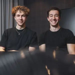 Sympathisches Porträt von zwei jungen Gründern in schwarzer Kleidung in ihren Büroräumen in Ulm.