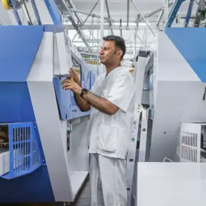 Ein Mitarbeiter einer Ulmer Reinigungsfirma bei der professionellen Bedienung einer großen Industriewaschmaschine in einer hellen Halle.