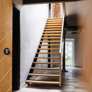 Eine freischwebende Holztreppe in einem hellen, modernen Flur mit Sichtbetonwand in einer Ulmer Immobilie.